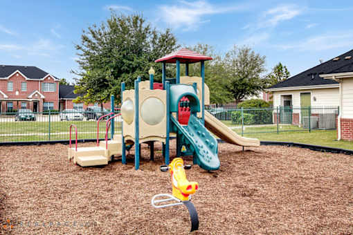A playground with a slide, swings, and a yellow toy.