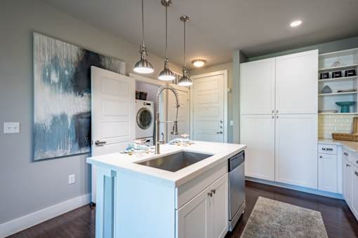 A modern kitchen with a large island and a painting on the wall.