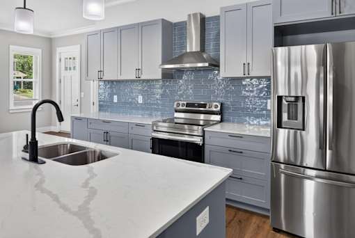 A modern kitchen with a stainless steel refrigerator and a marble countertop.