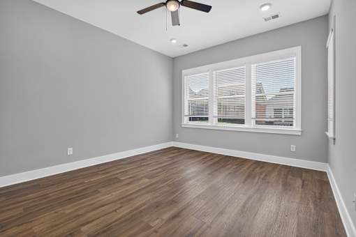 A room with a ceiling fan and wooden flooring.