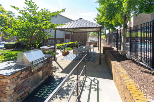 a patio with a grill and a gazebo in front of a building