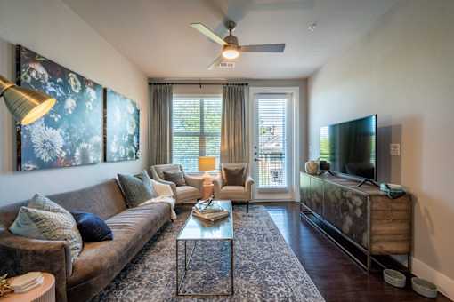 A living room with a brown couch, a glass coffee table, and a television on a wooden cabinet.