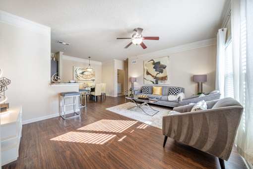 A living room with a grey couch and a wooden floor.