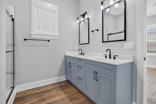 A bathroom with a double sink vanity and a mirror above it.