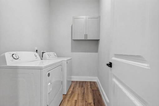 A white bathroom with a wooden floor and white cabinets.