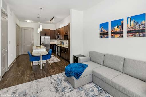 A modern kitchen with a dining table and a grey couch.