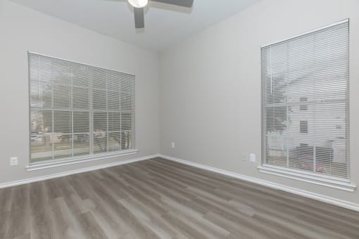 a bedroom with two windows and a ceiling fan