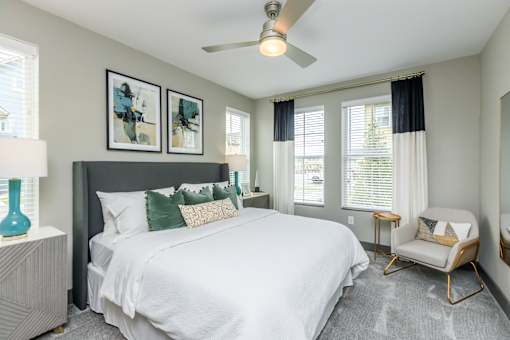A bedroom with a large bed, a ceiling fan, and a chair.