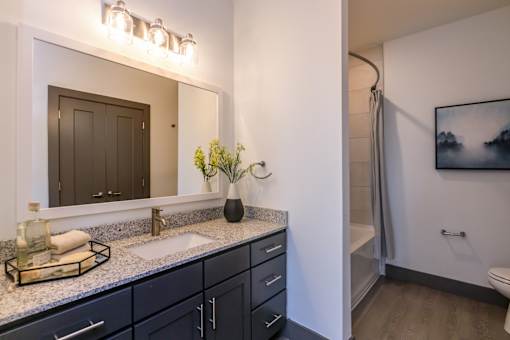 A bathroom with a sink, mirror, and a vase of flowers.