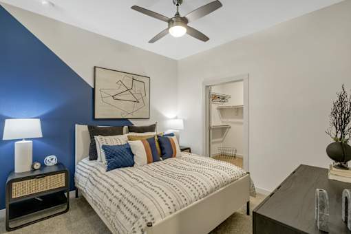 A bedroom with a bed, nightstand, and a ceiling fan.