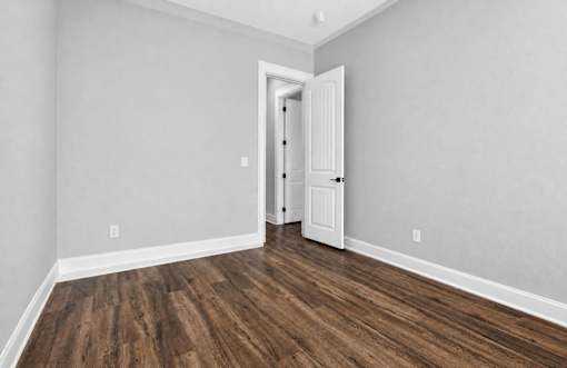 A room with a white door and wooden flooring.