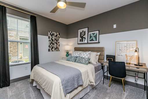 A bedroom with a bed, desk, and chair.
