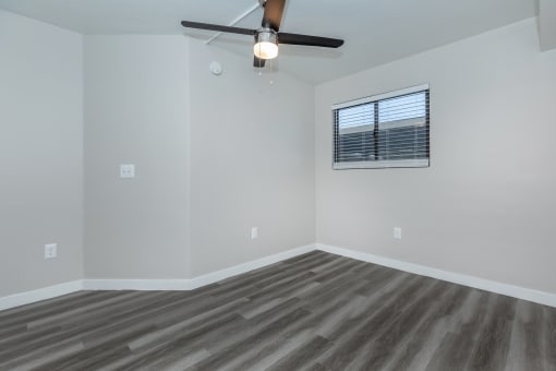 an empty living room with a ceiling fan and a window