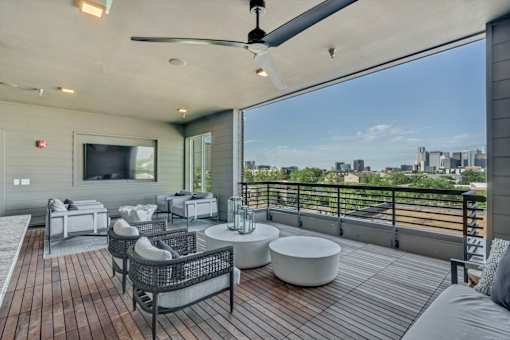 A patio with a ceiling fan and a view of the city.