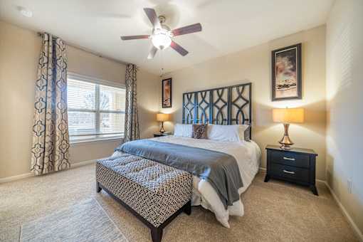 A bedroom with a large bed and a ceiling fan.