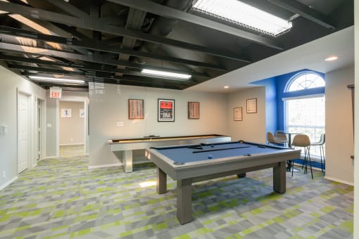a games room with two pool tables and chairs