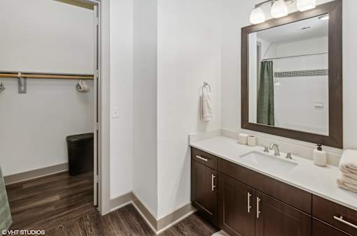 A bathroom with a white sink and brown cabinets.