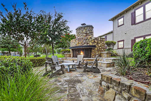 a patio with a stone fireplace and a table and chairs