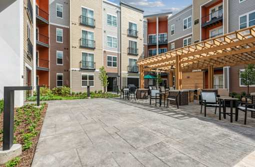 A patio area with a table and chairs is surrounded by apartment buildings.