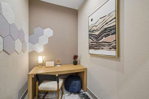 A room with a desk, chair, and a painting on the wall.