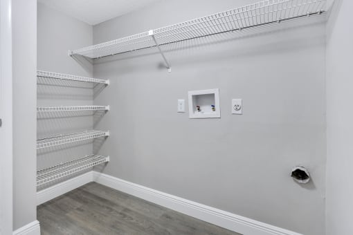 a room with white walls and a white closet with shelves