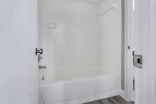 a white bathroom with a white tub and a white door