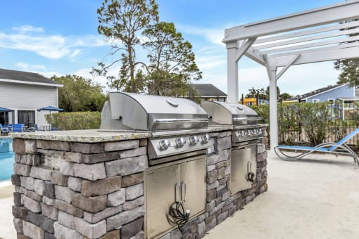 an outdoor kitchen with two stainless steel appliances and a grill