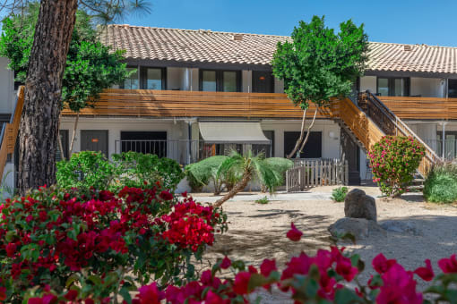 a view of a building with trees and flowers in front of it
