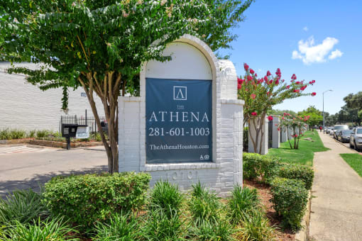 a building with a sign and some trees and plants