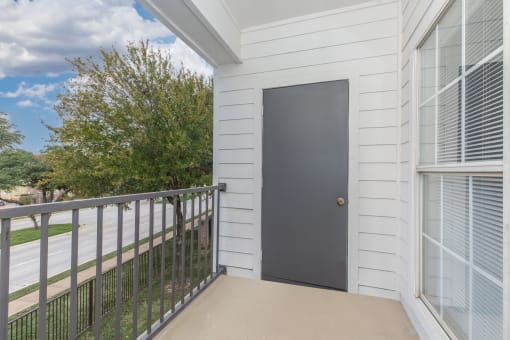 the balcony of a home with a black door and a metal railing