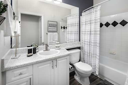 A white bathroom with a sink, toilet, and shower.