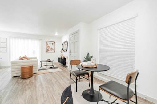 A living room with a white sofa, a black table, and a wooden chair.