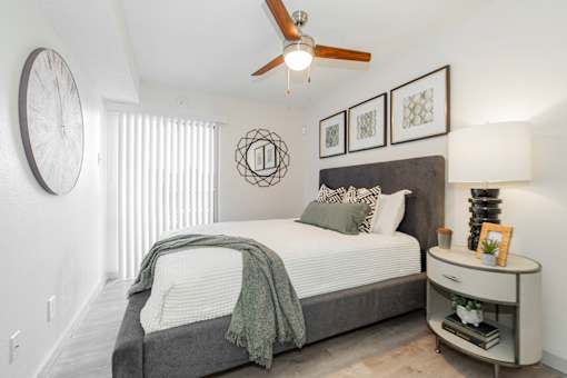 A bedroom with a bed, nightstand, and a ceiling fan.