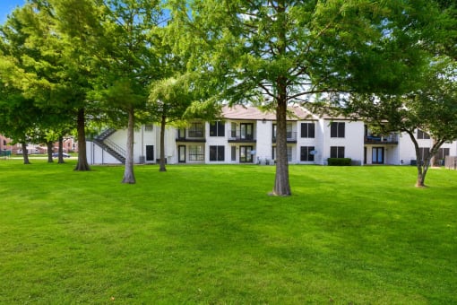 a grassy area with trees in front of a building