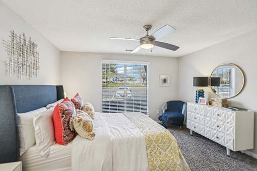 A bedroom with a bed, chair, and a dresser with a mirror.
