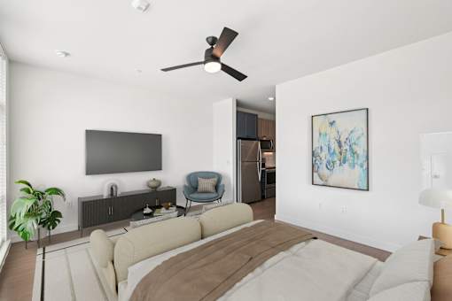 A living room with a couch, a ceiling fan, and a painting on the wall.