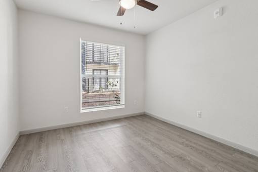 Empty room with a window and a fan on the ceiling.