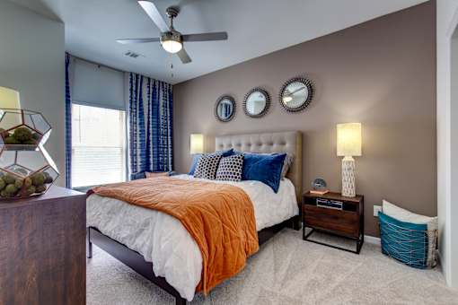 the master bedroom has a comfy bed and a ceiling fan