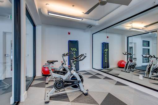 a fitness room with exercise bikes and a glass window