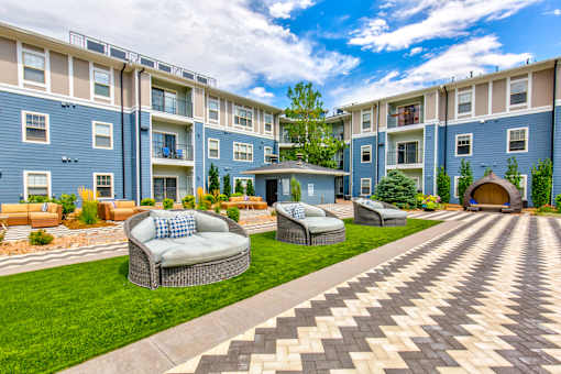 an outdoor area with couches and chairs in front of an apartment building