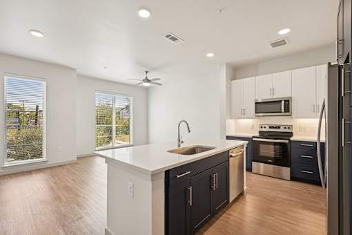 A modern kitchen with dark blue cabinets and stainless steel appliances.
