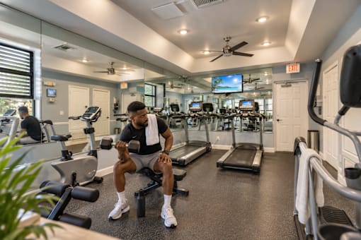 A man is working out in a gym with a variety of equipment.