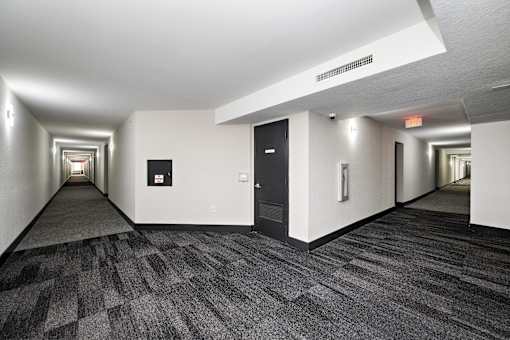 A long hallway with a carpeted floor and white walls.