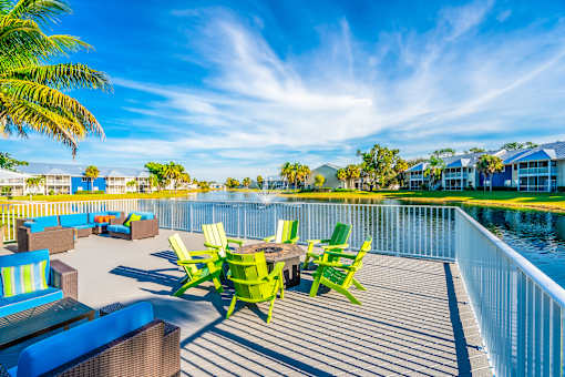 A sunny day at a poolside with a table and chairs.