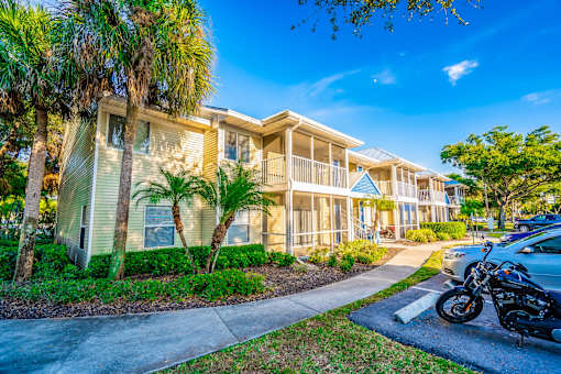 A motorcycle is parked on the sidewalk in front of a two-story building with a balcony.