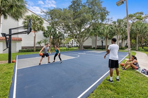 A man in a white shirt and black shorts is standing on a basketball court.