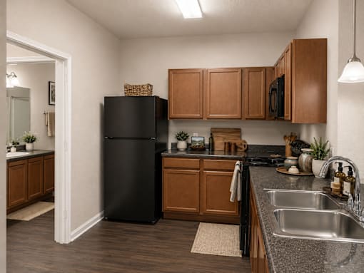 A kitchen with a black refrigerator and wooden cabinets.