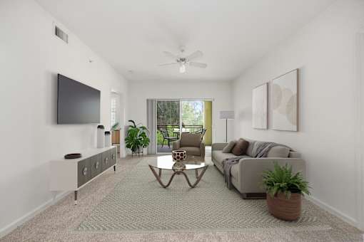 A living room with a grey sofa, a coffee table, and a flat screen TV mounted on the wall.