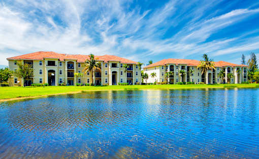A row of houses with red roofs and white walls are reflected in the water.