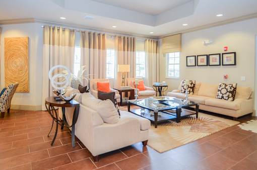 A living room with a white sofa, a coffee table, and a glass table with a vase on it.